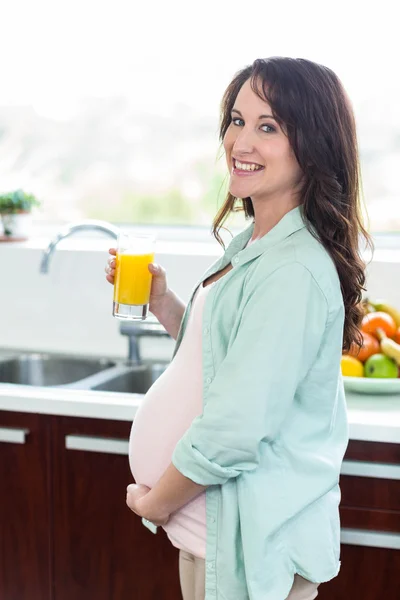 Těhotná žena hospodářství pomerančový džus — Stock fotografie
