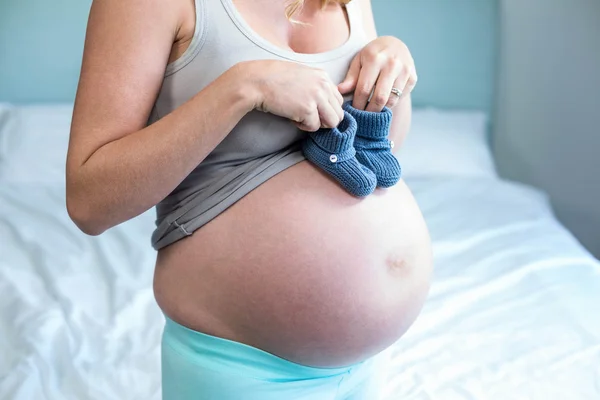 Zwangere vrouw met gebreide sloffen op haar buik — Stockfoto