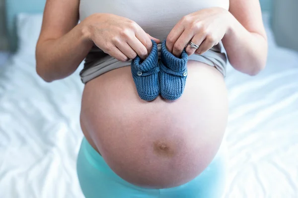 Zwangere vrouw met gebreide sloffen — Stockfoto
