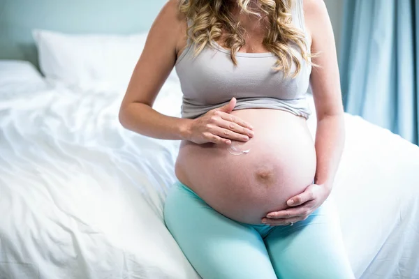 Mulher grávida aplicando creme em sua barriga — Fotografia de Stock