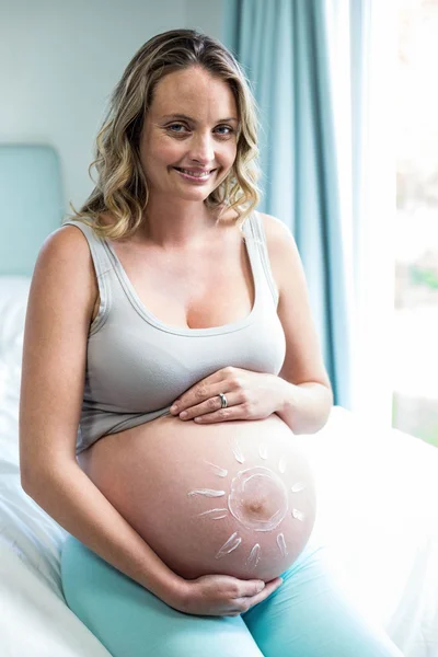 Gravid kvinne som smører krem på magen – stockfoto