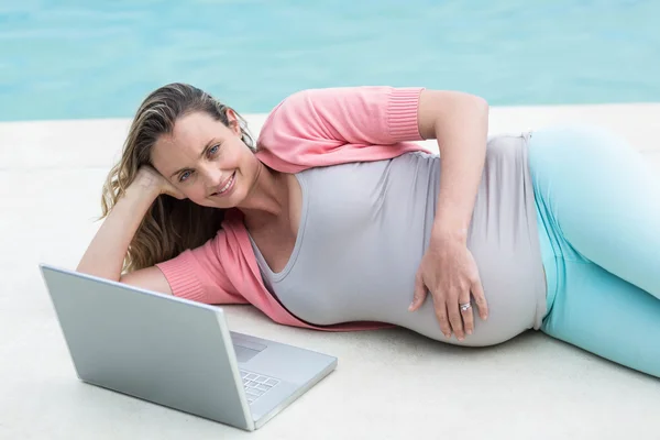 Mulher grávida relaxante fora usando laptop — Fotografia de Stock