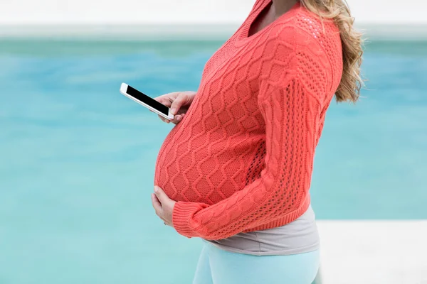 Femme enceinte touchant son ventre et textos — Photo