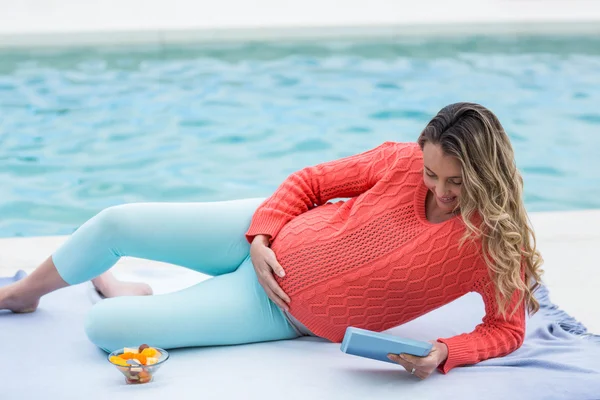 Mulher grávida relaxando fora e usando tablet — Fotografia de Stock