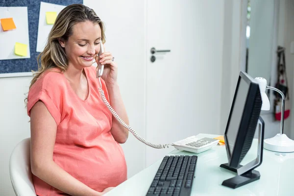 Mulher grávida usando computador e telefone — Fotografia de Stock