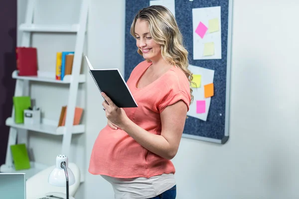 Mujer embarazada leyendo un cuaderno — Foto de Stock