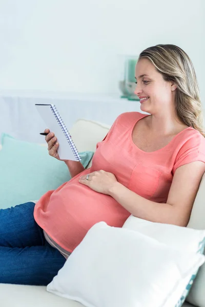 Mujer embarazada escribiendo en bloc de notas — Foto de Stock
