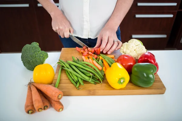 Pregnant woman cutting vegetables — Stock Photo, Image