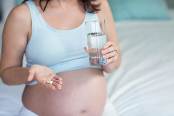 Femme enceinte prenant une pilule avec de l'eau — Photo