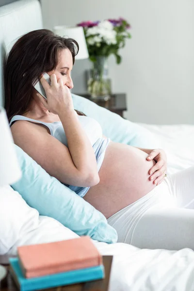 Gravid kvinna i sängen att göra ett telefonsamtal — Stockfoto