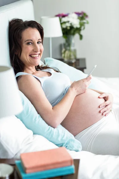 임신한 여자 문자 메시지 침대에 누워 — 스톡 사진
