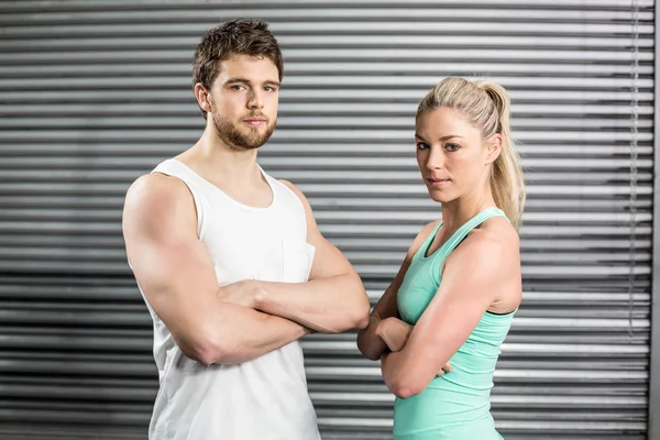 Fit couple posing with arms crossed