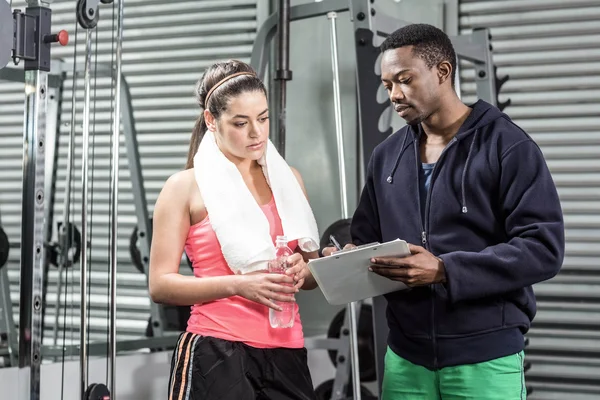 Entrenador y mujer mirando el plan de entrenamiento — Foto de Stock