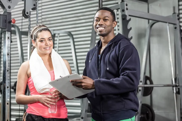 Formateur et femme regardant le plan d'entraînement — Photo