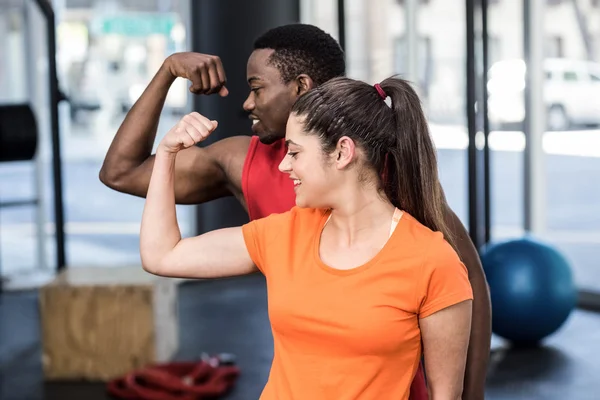 Mujer sonriente y hombre contrayendo bíceps — Foto de Stock