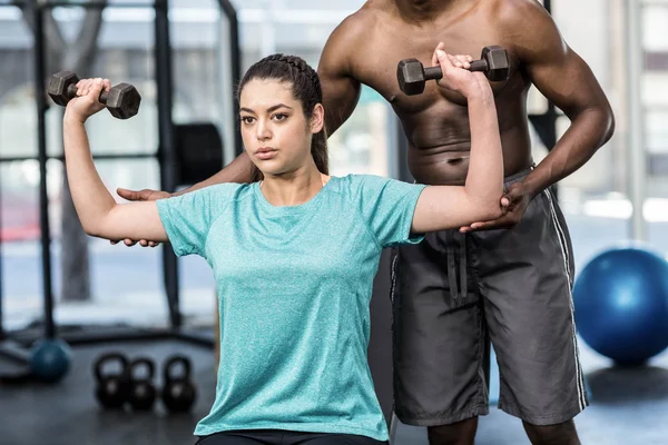 Athletic woman lifting weights helped by trainer — Stock Photo, Image