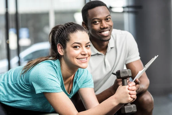 Athletic woman lifting weights helped by trainer — Stock Photo, Image