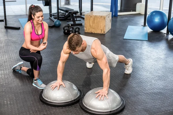 Hombre haciendo ejercicio ayudado por entrenador mujer — Foto de Stock