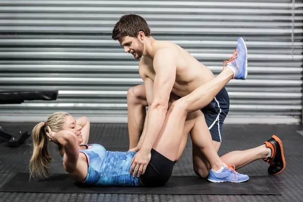 Entrenador masculino que ayuda a la mujer con abdominales — Foto de Stock