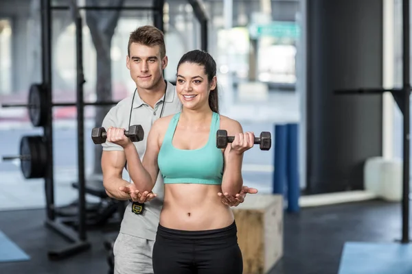 Treinador masculino auxiliando mulher levantando halteres — Fotografia de Stock