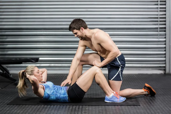 Entrenador masculino que ayuda a la mujer con abdominales — Foto de Stock