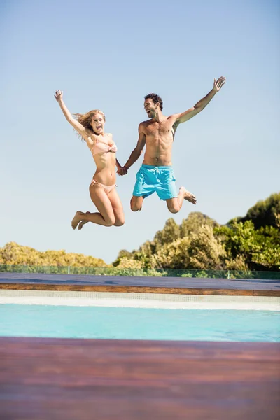 Casal feliz pulando na piscina — Fotografia de Stock