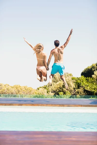Casal feliz pulando na piscina — Fotografia de Stock
