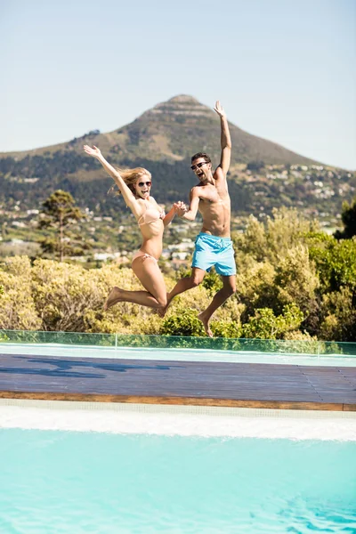 Glückliches Paar springt in den Pool — Stockfoto