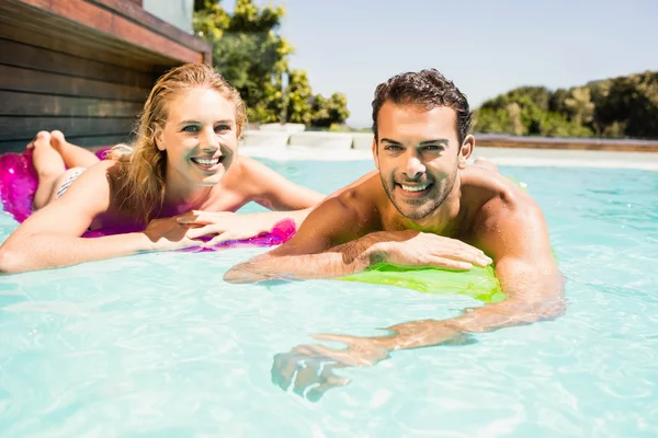 Lyckliga par med lilos i poolen — Stockfoto