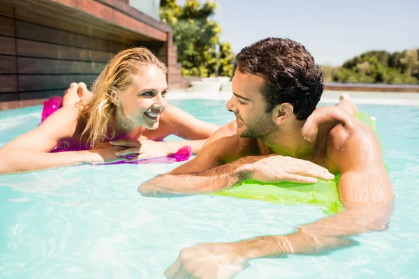 Pareja feliz con lilos en la piscina —  Fotos de Stock