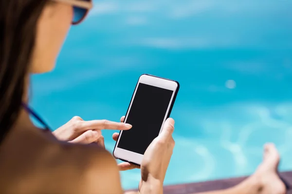 Brunette met smartphone aan het zwembad — Stockfoto