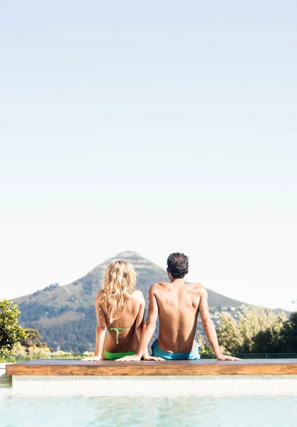 Вид сзади на пару, сидящую у бассейна — стоковое фото