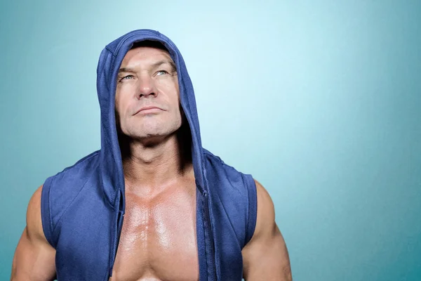 Muscular man in blue hood looking up — Stock Photo, Image