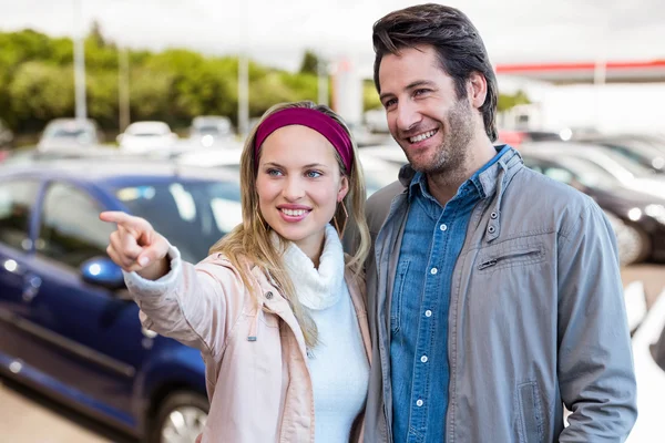 Zusammengesetztes Bild eines lächelnden Paares, das schaut und zeigt — Stockfoto