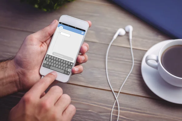 Person holding smart phone at desk — Stock Photo, Image