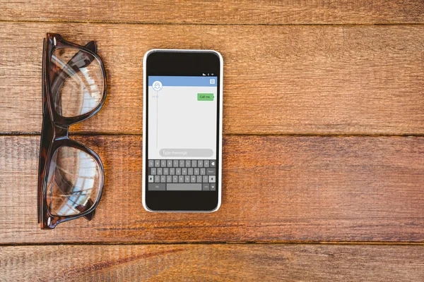 Очки и смартфон на столе — стоковое фото