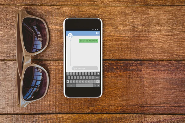 Occhiali e uno smartphone sul tavolo — Foto Stock