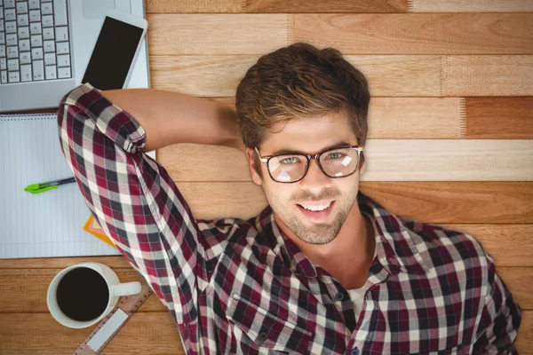 Hipster sonriendo mientras miente por el ordenador portátil — Foto de Stock