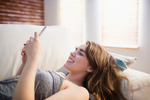 Hübsche Frau liegt mit Handy auf der Couch — Stockfoto