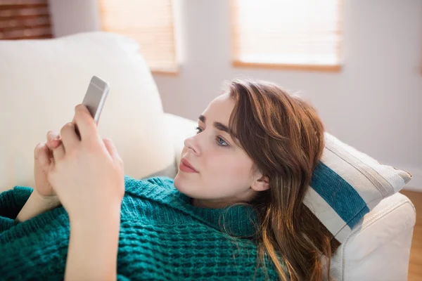 Ładna kobieta, leżąc na kanapie przy użyciu telefonu — Zdjęcie stockowe