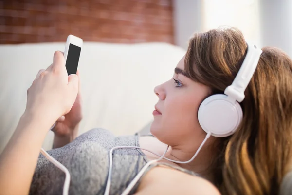 Mujer acostada en el sofá usando su teléfono —  Fotos de Stock