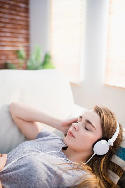 Mulher bonita deitada no sofá ouvindo música — Fotografia de Stock