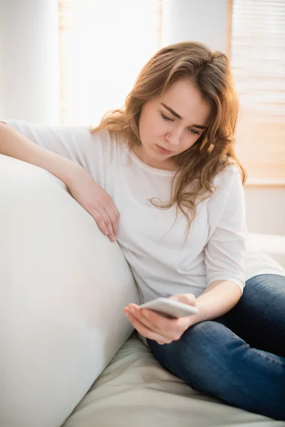 Traurige Frau schaut auf ihr Handy — Stockfoto