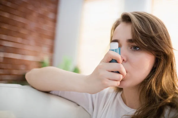 Mujer usando su inhalador en el sofá — Foto de Stock