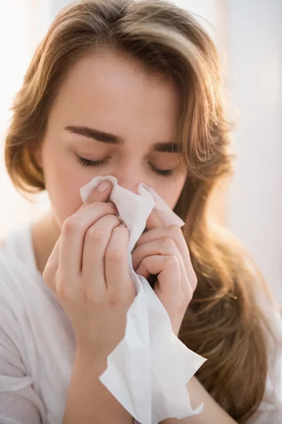 Mujer sonándose la nariz en el sofá — Foto de Stock