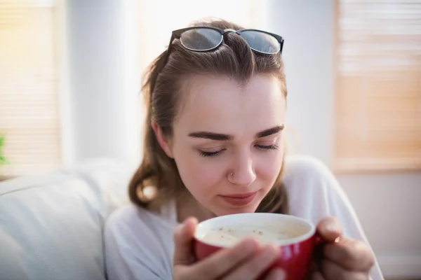 Kadın kahve ile kanepede rahatlatıcı — Stok fotoğraf