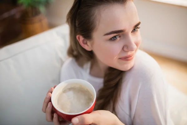 Güzel kadın kahve ile kanepede rahatlatıcı — Stok fotoğraf