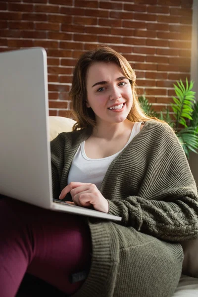 Mulher bonita usando laptop deitado no sofá — Fotografia de Stock