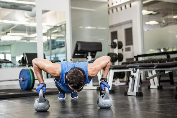 Bello uomo fare push up con kettlebells — Foto Stock