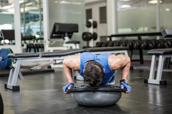 Gespierde man doet duw omhoog met bosu bal — Stockfoto